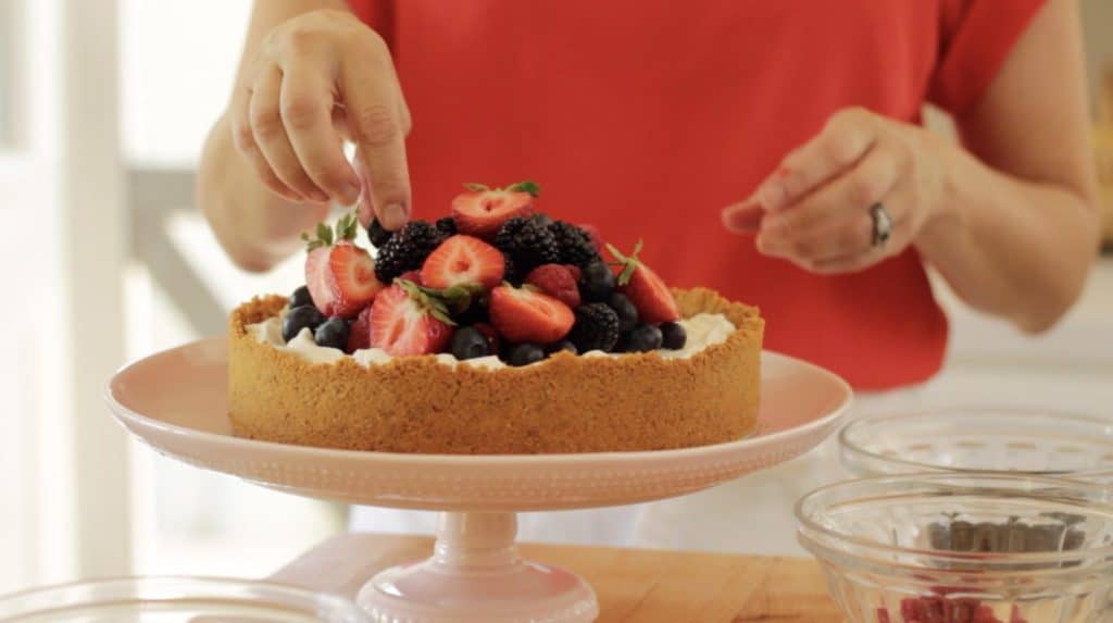 decorating a no-bake cheesecake with fresh fruit