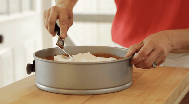 Spreading out cream cheese filling to a cooled graham cracker crust