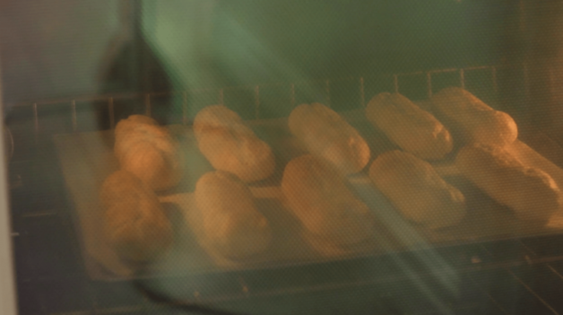 Eclair shells being baked in the oven on a metal tray