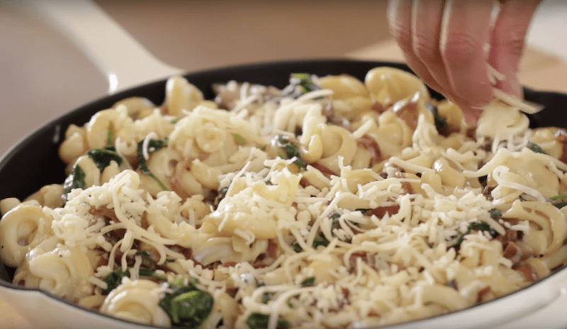 Grated cheese is added on top of a Pasta Bake with Veggies 