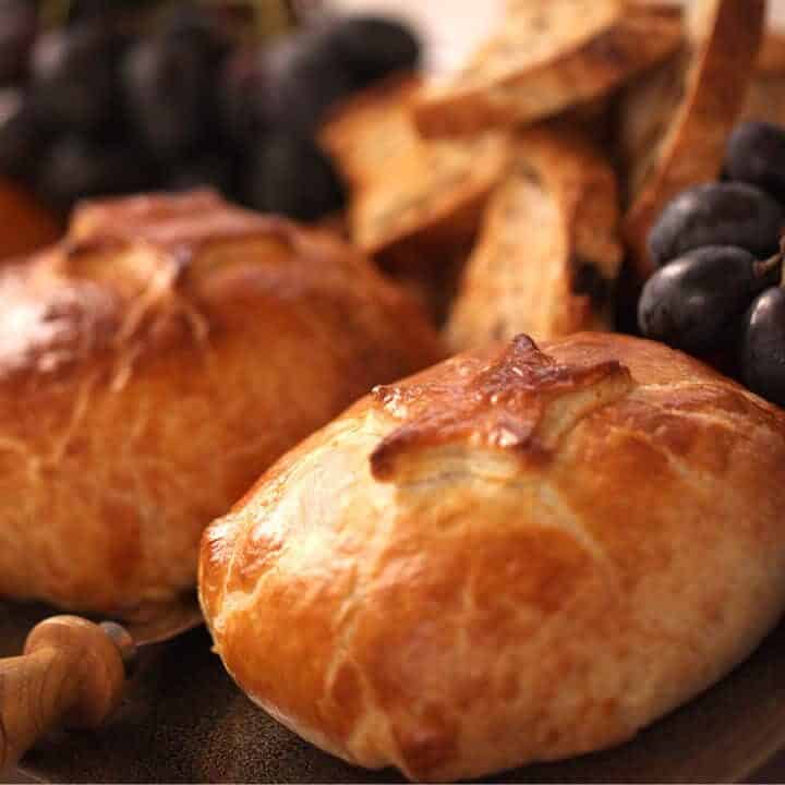 A platter of Baked Brie in Puff Pastry served with fresh grapes