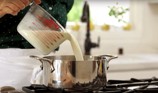 milk is added to a large pot on a cooktop