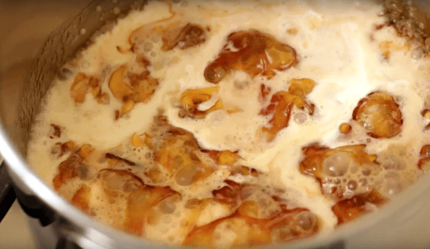 cream being added to hot caramel in a large pot 