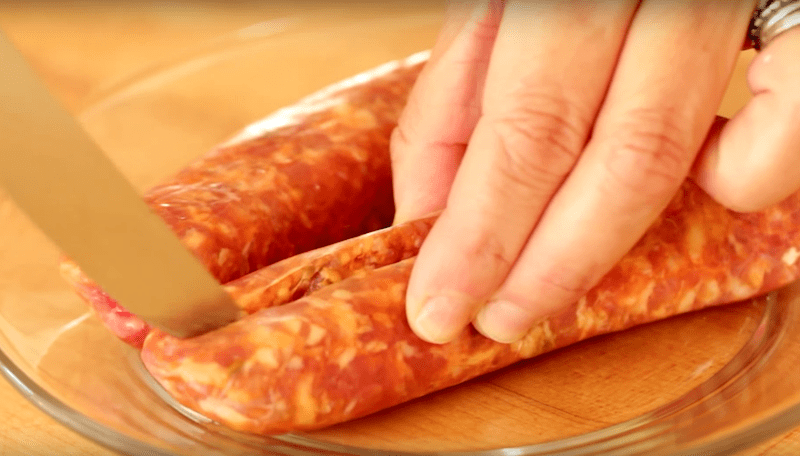 Italian sausage being cut out of its casing 