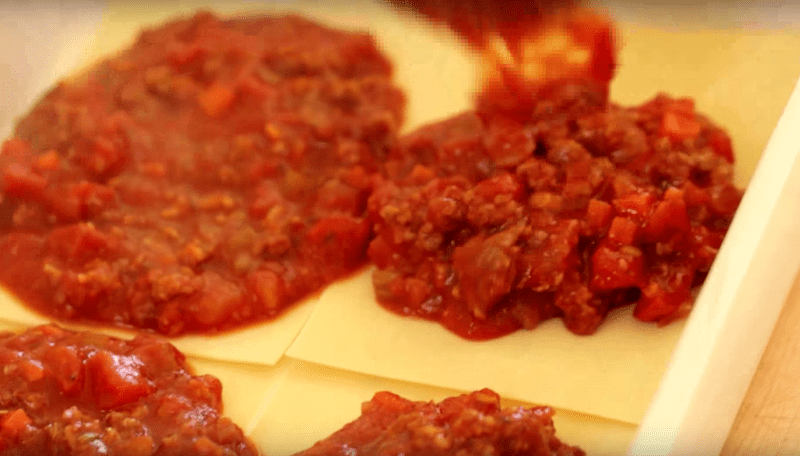 meat sauce being added on top of lasagna noodles