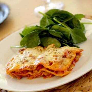Lasagna recipe served with salad on a white plate