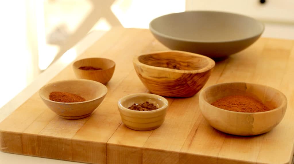 A selection of spices in small bowls on a cutting board 