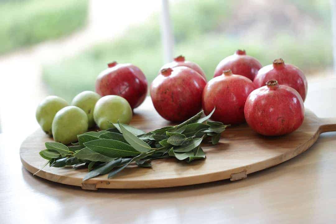 Pomegranates, pears and bay leaves on a cutting board