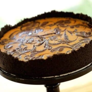 Pumpkin Cheesecake with Chocolate Swirl served on a cake stand on a wood surface