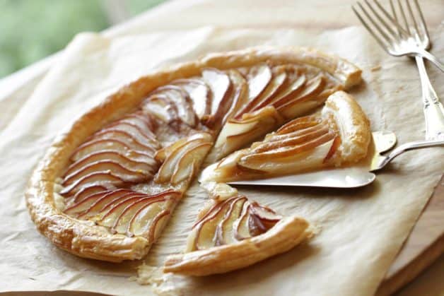 Pear Tart with Puff Pastry on cutting board with parchment paper and forks