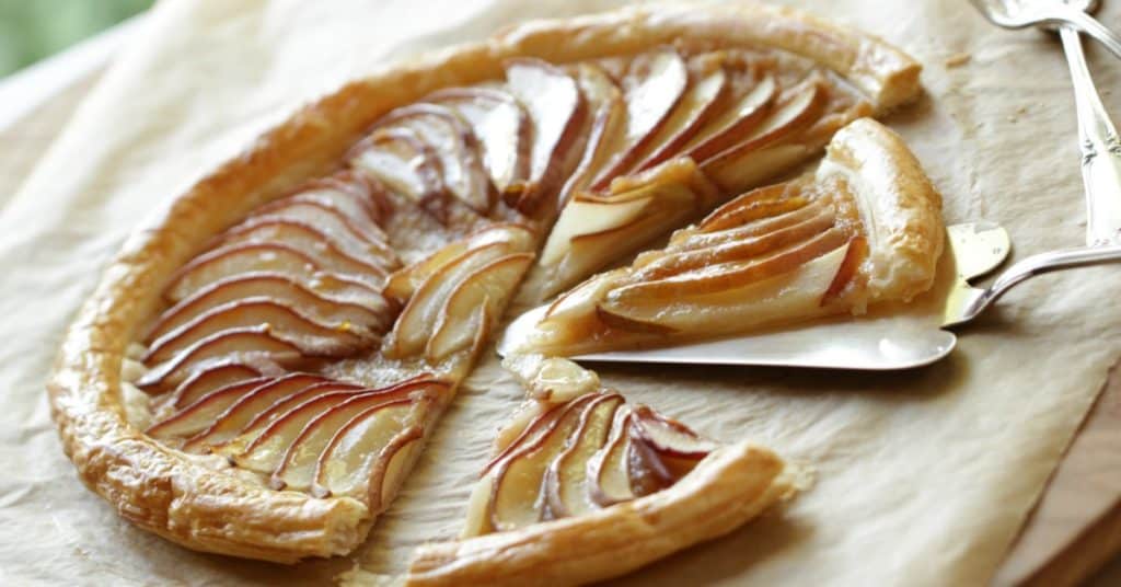 Pear tart with puff pastry sliced on parchment paper