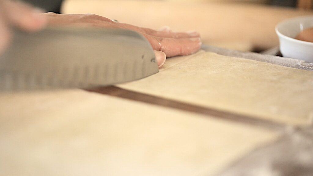 a person cutting puff pastry sheets into rectangles