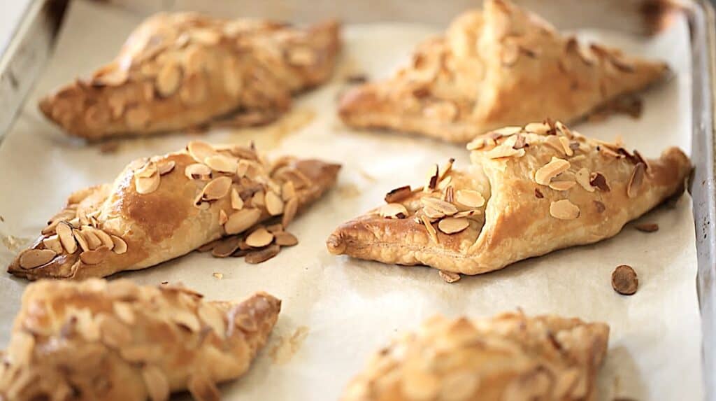 freshly baked almond croissants on a sheet pan