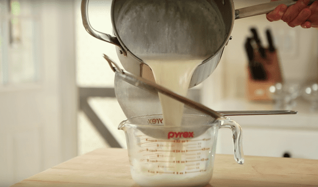 cranberry panna cotta recipe being poured into a strainer