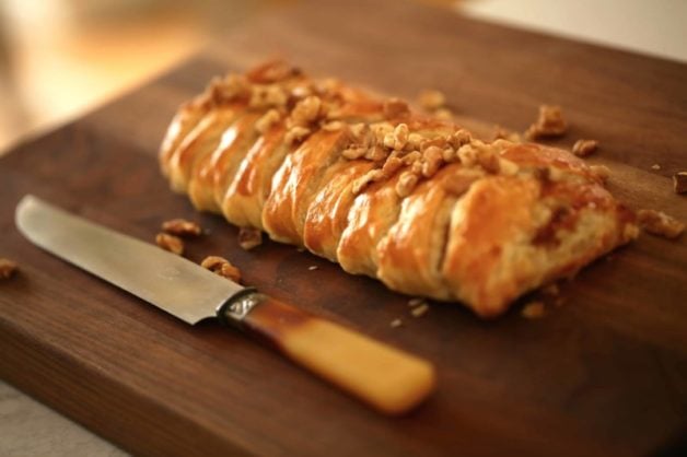 Fig and Brie Braid freshly baked on a walnut board with knife