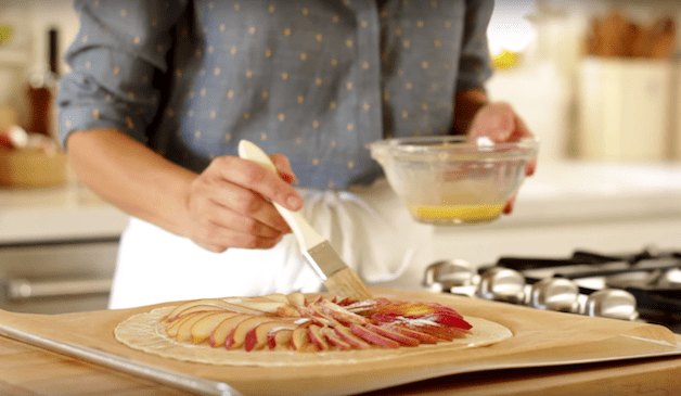 egg wash being brushed on top of a pear tart recipe before baking