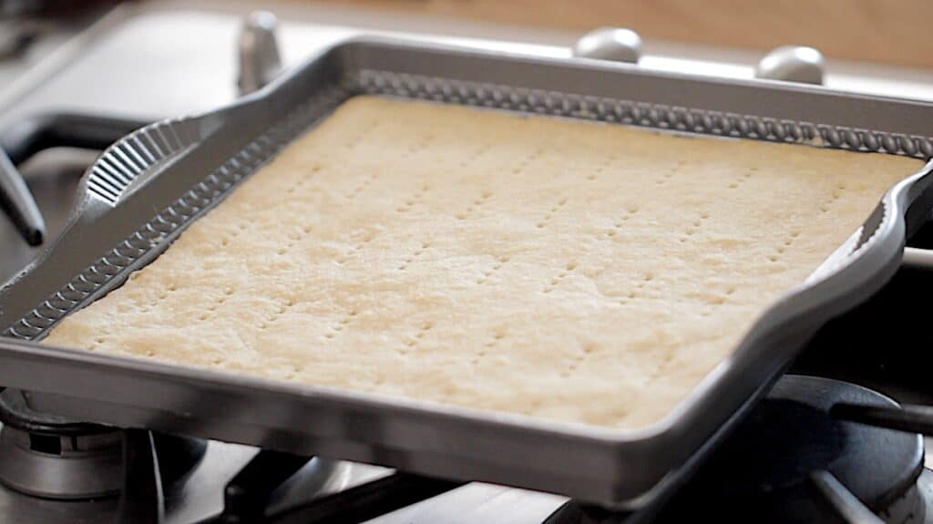 a shortbread pan cooling on cooktop with freshly baked shortbread