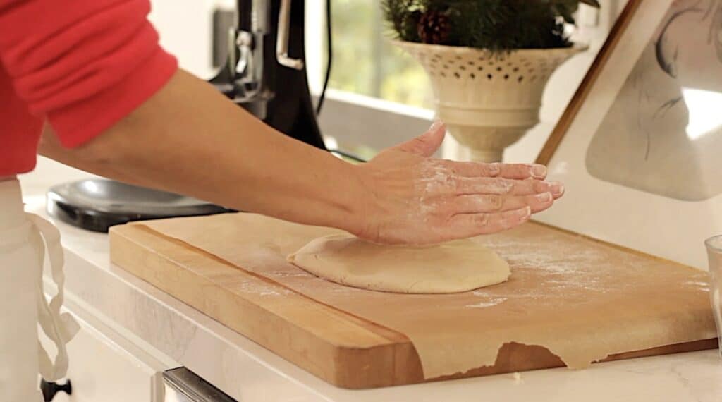 A person pressing shortbread dough down onto parchment paper