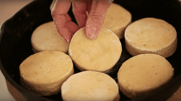 Biscuits being added to a cast iron skillet before baking