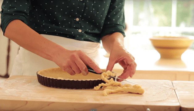 tart dough being trimmed into a tart pan 