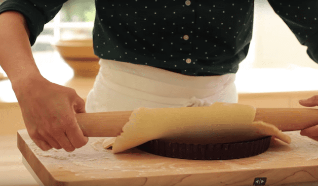 tart dough being rolled in to a tart tin 