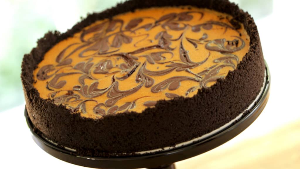 Pumpkin Cheesecake with Chocolate Swirl served on a black cake stand 