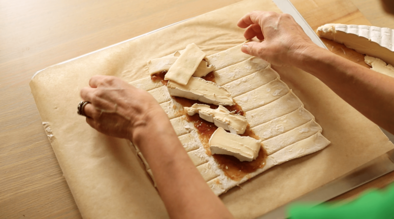 Creating a braid of fig and brie cheese on a sheet of puff pastry on a cookie sheet