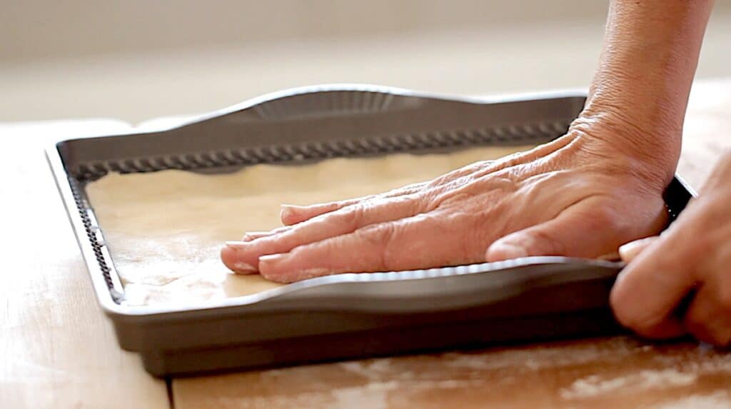 pressing dough into pan 