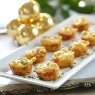 a white platter of mac and cheese bites with a fresh chive garnish