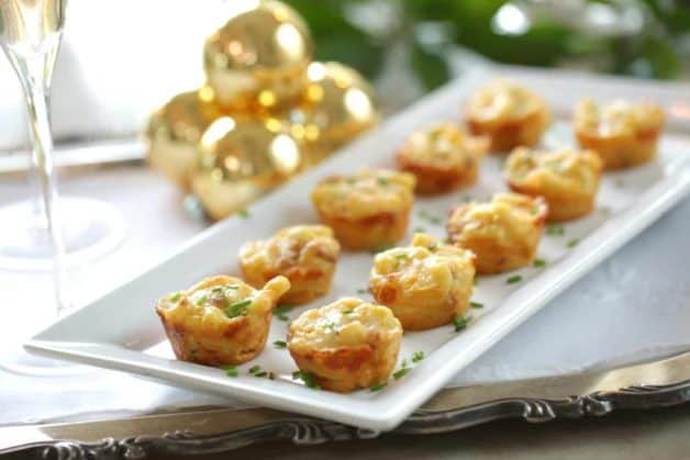 a white platter of mac and cheese bites with a fresh chive garnish