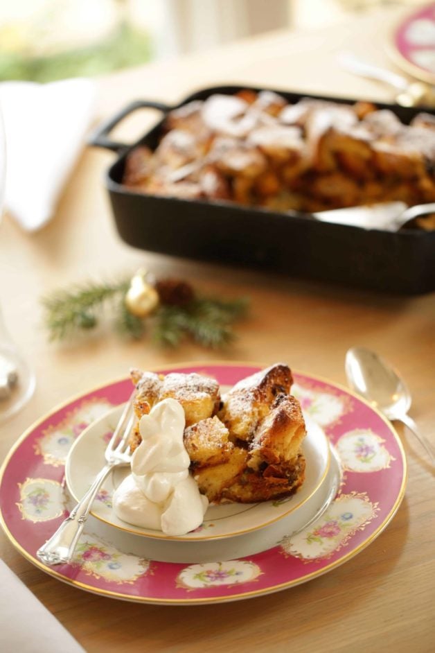 Panettone Bread Pudding on a serving on a plate with whipped cream and casserole in the background