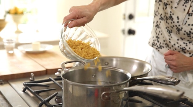 Placing pasta in a pot of boiling water for Mac and Cheese Bites