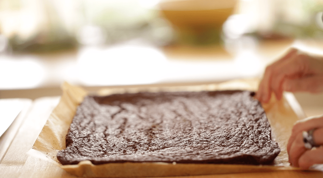 A pan of freshly baked brownies in a sheet pan lined with parchment paper