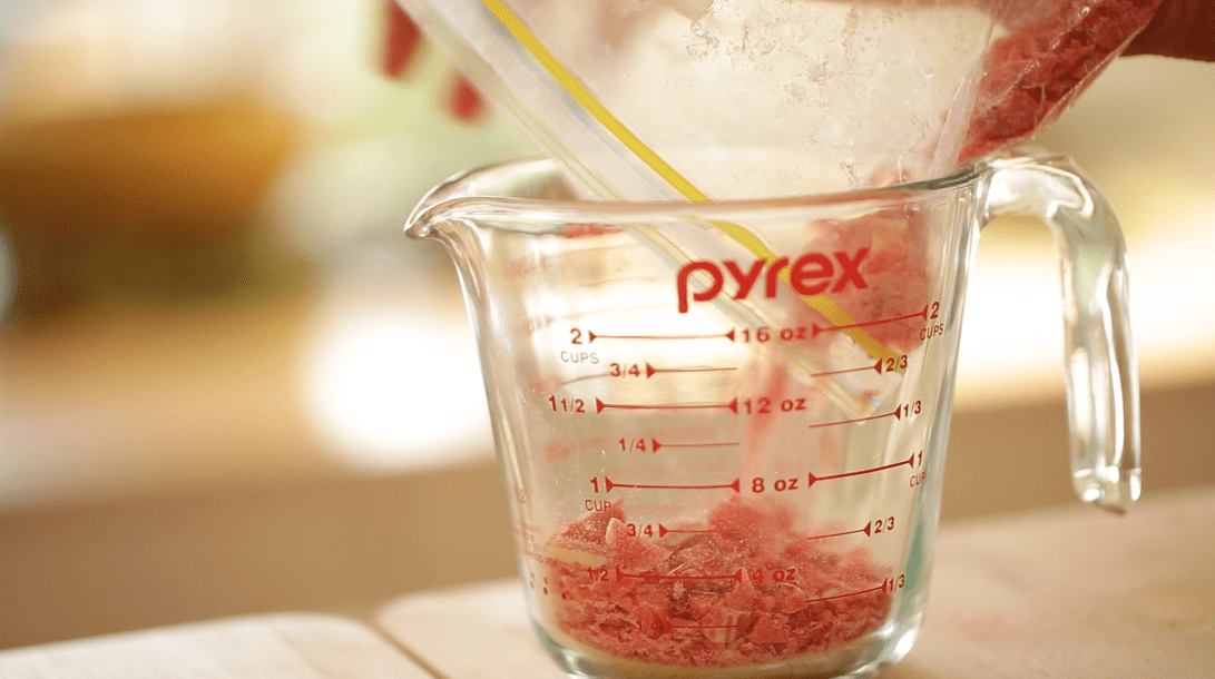 Crushed Candy Canes in a Zip Lock bag going into a Pyrex Pitcher