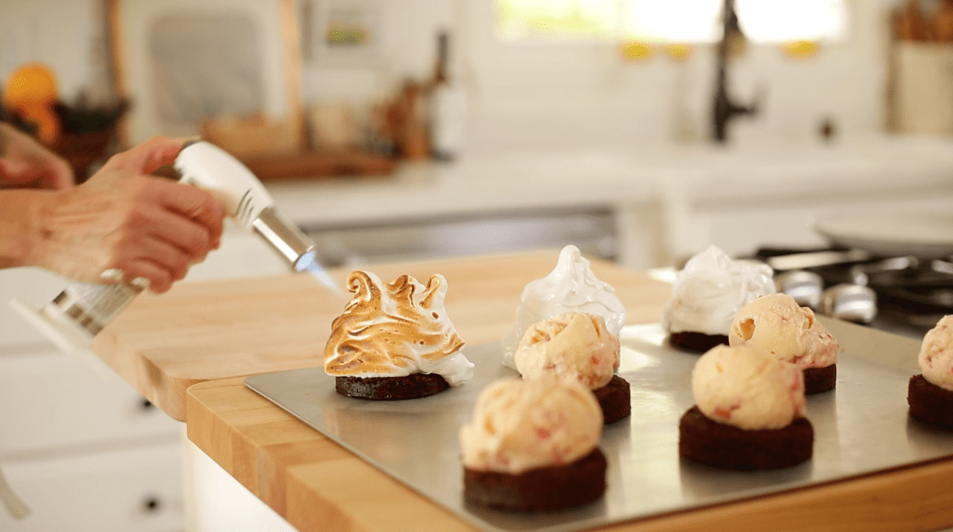 Toasting mini baked alaskas covered in meringue with a kitchen torch