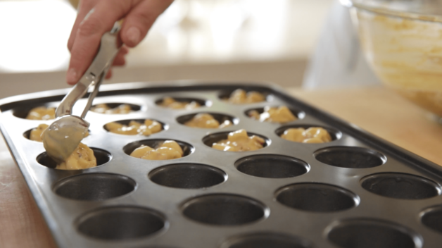 Bacon Mac & Cheese Bites being scooped into a mini muffin tin before baking