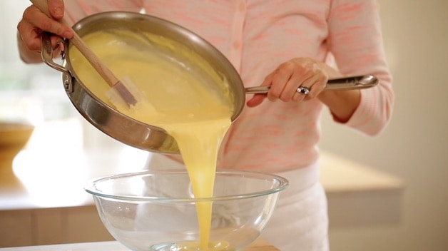 pouring souffle base into a large bowl from a skillet