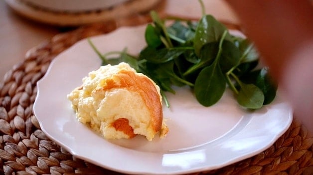 a scoop of cheese souffle on a plate with a salad