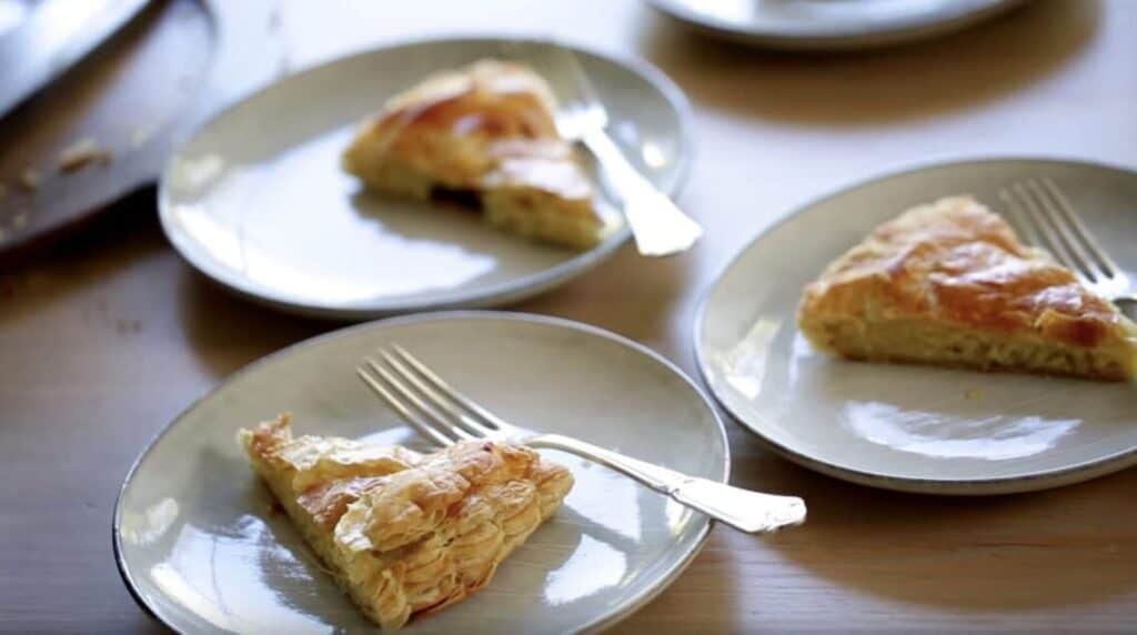 Slices of Galette des Rois cake on gray plates with forks