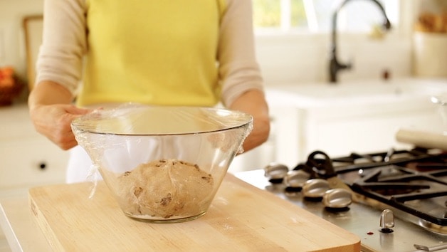 Dough ball in bowl covered with plastic wrap