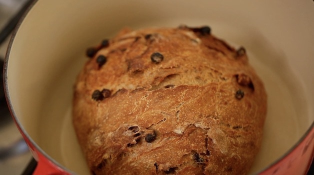 A loaf of baked cinnamon raisin bread in a Dutch oven
