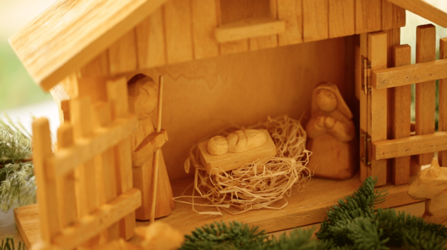 Nativity scene made from wood showing Jesus Mary and Joseph in the manger