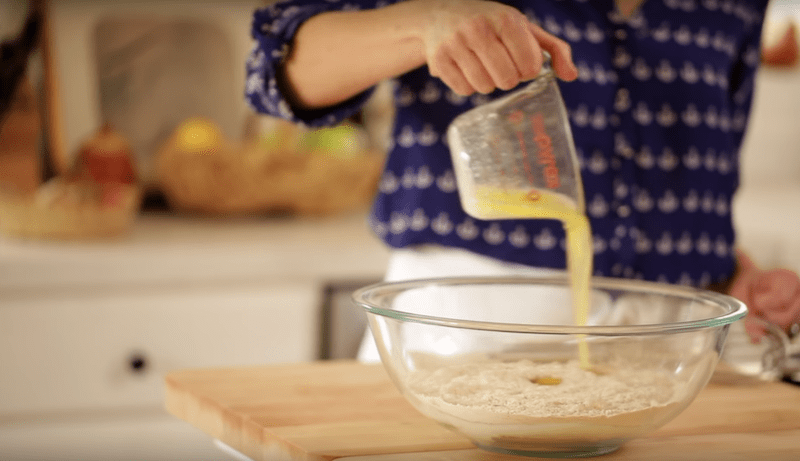 melted butter poured into dry ingredients in a large clear bowl for a banana pancake recipe
