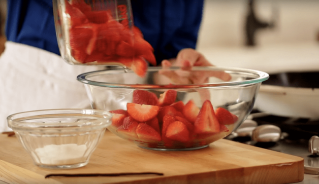 placing cut strawberries in a bowl