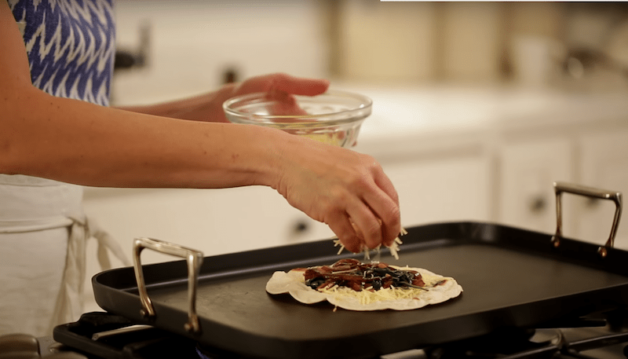 cheese being added to quesadilla cooking on a griddle for a Veggie Quesadilla Recipe with Chunky Guacamole 