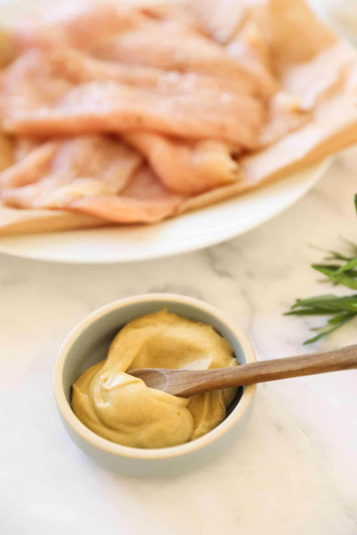 A dish of Dijon Mustard with Chicken Cutlets in the Background