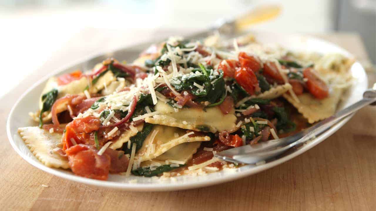Spinach Ravioli with Spinach, Tomatoes, and Caramelized Onions on a white platter