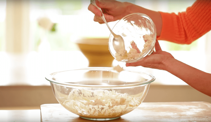 crab being added to a clear bowl for an easy crab cake recipe