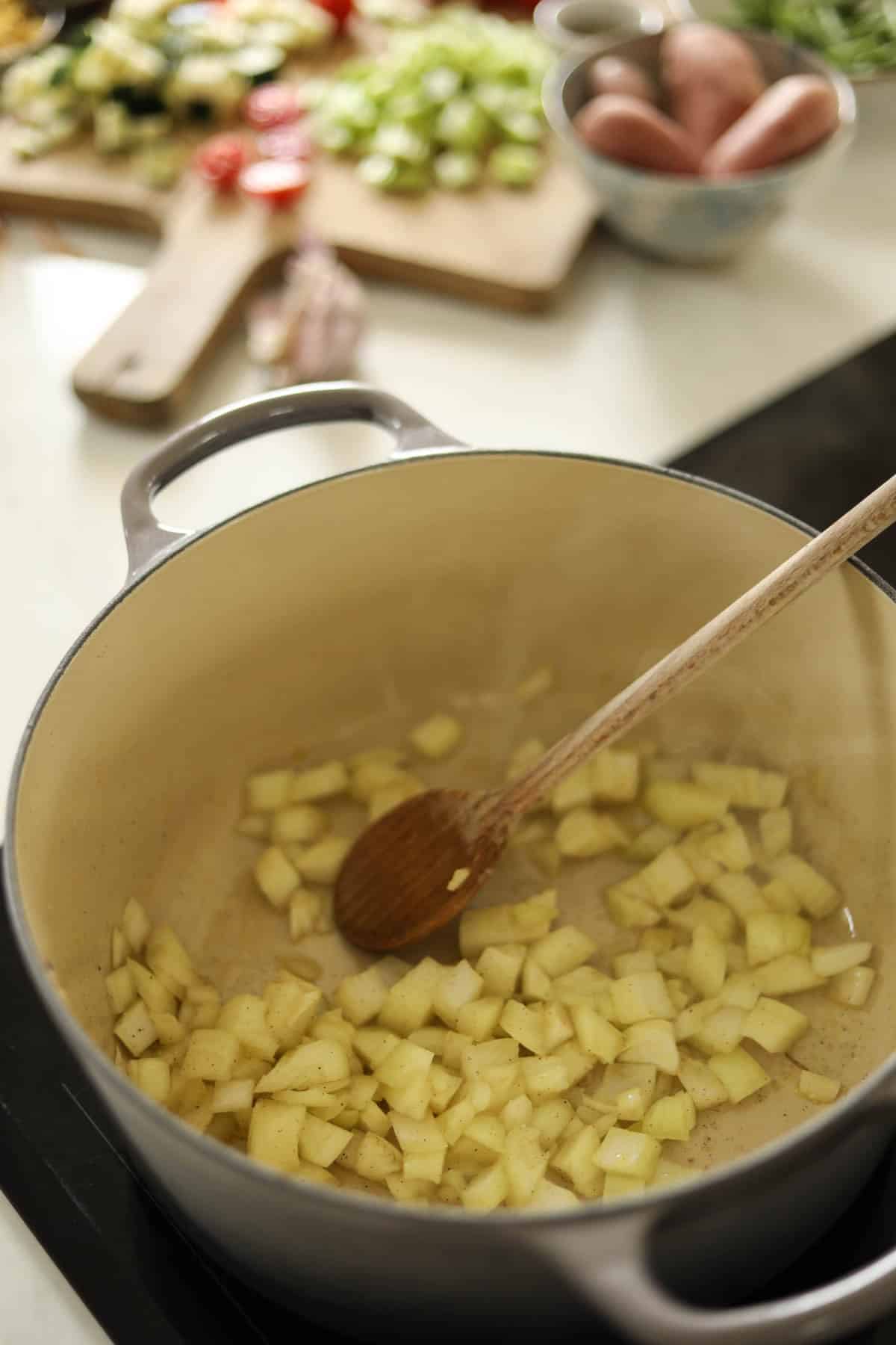 Onions cooking in a gray Dutch oven.
