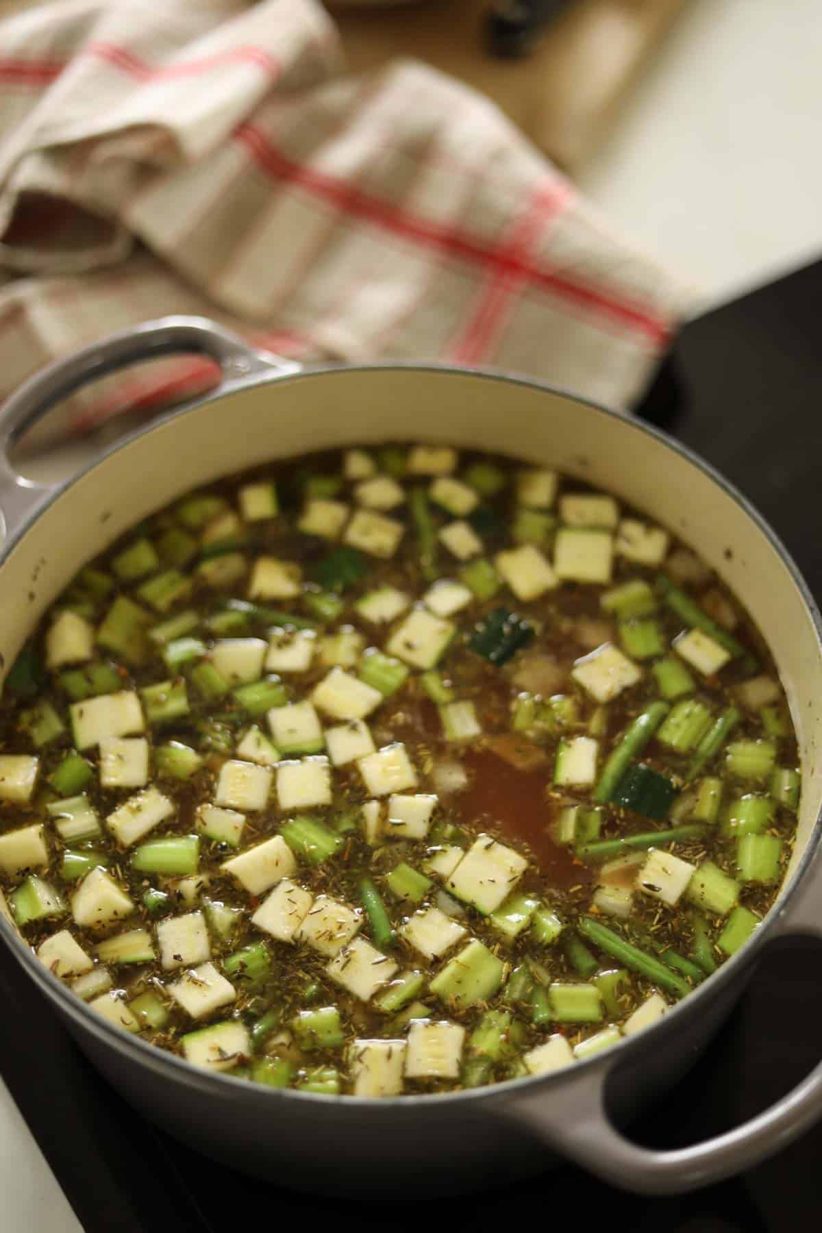 A large dutch oven filled with vegetables and broth.